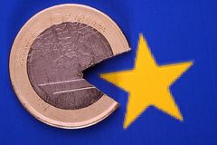 Eine kaputte Ein-Euro-Münze vor dem Europa-Symbol