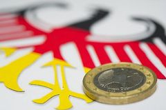Eine Euro-Münze liegt auf dem deutschen Bundesadler in Nationalfarben