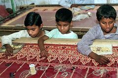 Drei Jungen besticken in einer Textilfabrik