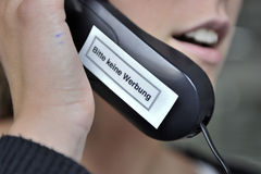 Eine Frau telefoniert mit einem Telefon, auf dem ein Aufkleber 