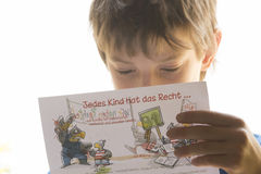 Ein Junge liest einen Flyer über die Rechte von Kindern