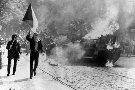 Demonstranten mit der tschechischen Flagge am 21.08.1968 in Prag neben einem brennenden sowjetischen Panzer.