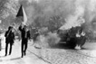 Demonstranten mit der tschechischen Flagge am 21.08.1968 in Prag neben einem brennenden sowjetischen Panzer.