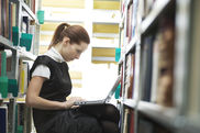 Junge Frau mit Laptop in einer Bibliothek
