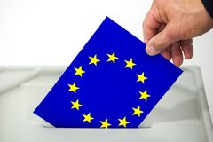 Ein Mann wirft eine Wahlkarte in Form der EU-Fahne in eine Urne.