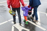 Ein Kind spaziert zusammen mit zwei Vätern über eine Straße
