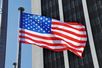 wehende USA-Fahne vor Bürohochhaus
