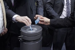 Stimmkarten werden in die Wahlurne gesteckt.