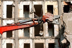 Ein Spezialbagger mit hydraulischer Zange schneidet aus einem der ältesten Hochhäuser von Schwerin eine Betonwand heraus