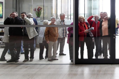 Besucher des Reichstagsgebäudes blicken durch eine Glaswand in Richtung Plenarsaal.