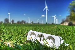 Steckdose auf einer Wiese vor Windrädern