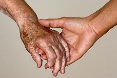 Ein ältere Hand wird von einer jüngeren Hand gehalten.