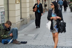 Eine hübsche Frau mit Sonnenbrille läuft vorbei an einem Bettler.