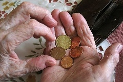 Hände einer alte Frau halten Münzen über einem Portmonee