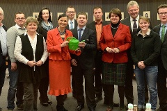 Gitta Connemann (links) erhält von Matthias Daun (rechts) im Beisein der Obleute und der Staatssekretärin im Landwirtschaftsministerium sowie Vertretern der Landjugend eine Gießkanne.