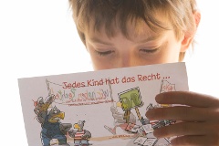 Ein Junge liest einen Fleyer über die Rechte von Kindern.