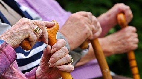 Senioren sitzen mit Gehstöcken auf einer Parkbank