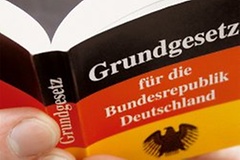 Symbolbild: Hand hält das Grundgesetz für die Bundesrepublik Deutschland
