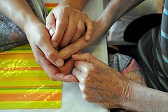 Eine Altenpflegerin hält die Hände einer alten Frau.