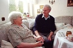 Älteres Rentner-Ehepaar im Wohnzimmer.