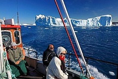 Urlauber an Deck eines Ausflugsbootes zwischen den Eisbergen bei Ilulissat, Diskobucht, Westküste, Grönland