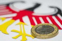 Eine Euro-Münze liegt auf dem deutschen Bundesadler in Nationalfarben