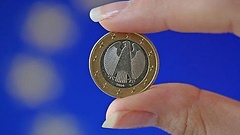 Fra hält Euro-Münze zwischen zwei Fingern