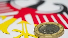 Eine Euro-Münze liegt auf dem deutschen Bundesadler in Nationalfarben