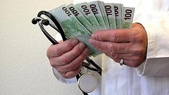 Ein Arzt hält ein Stetoskop sowie etliche 100-Euro-Scheine in der Hand.