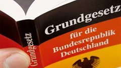 Symbolbild: Hand hält das Grundgesetz für die Bundesrepublik Deutschland