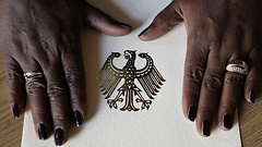 Die Hände einer Schwarzafrikanerin liegen auf einer Einbürgerungsurkunde.