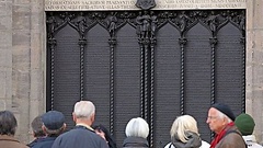 Touristen stehen vor Luthers Thesen in der Lutherstadt Wittenberg.