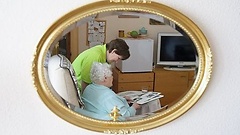 Eine Pflegekraft und eine ältere Dame schauen sich gemeinsam eine Fotoalbum an.