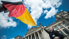Plenarsaalassistent Jose Cases wechselt die Flagge der Einheit vor dem Reichstagsgebäude.