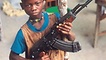 farbiger Junge, der ein Maschinengewehr hält