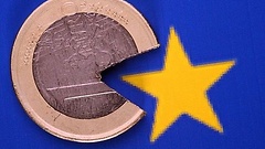 Eine kaputte Ein-Euro-Münze vor dem Europa-Symbol
