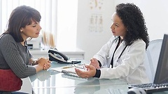 Patientin und Ärztin führen ein Gespräch am Tisch