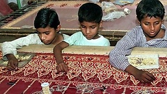 Drei Jungen besticken in einer Textilfabrik