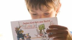 Ein Junge liest einen Fleyer über die Rechte von Kindern.