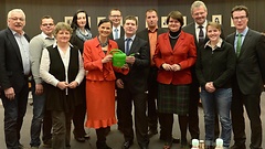 Gitta Connemann (links) erhält von Matthias Daun (rechts) im Beisein der Obleute und der Staatssekretärin im Landwirtschaftsministerium sowie Vertretern der Landjugend eine Gießkanne.